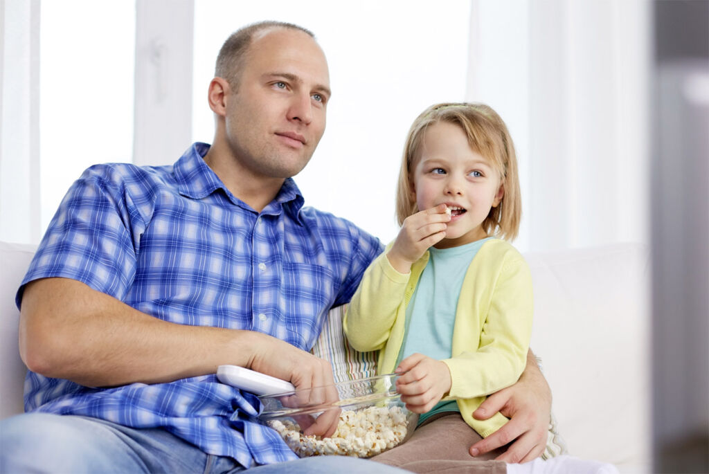 A father eating popcorn with his daughter