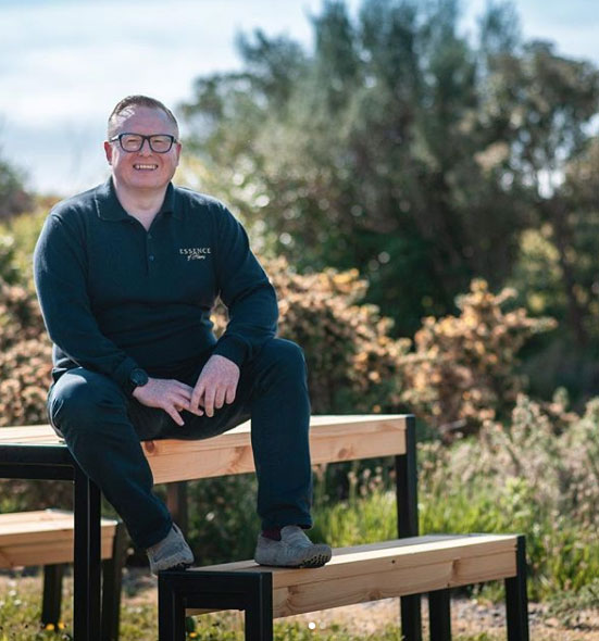 Jamie McGowan sitting on a bench in the grounds of the business premises