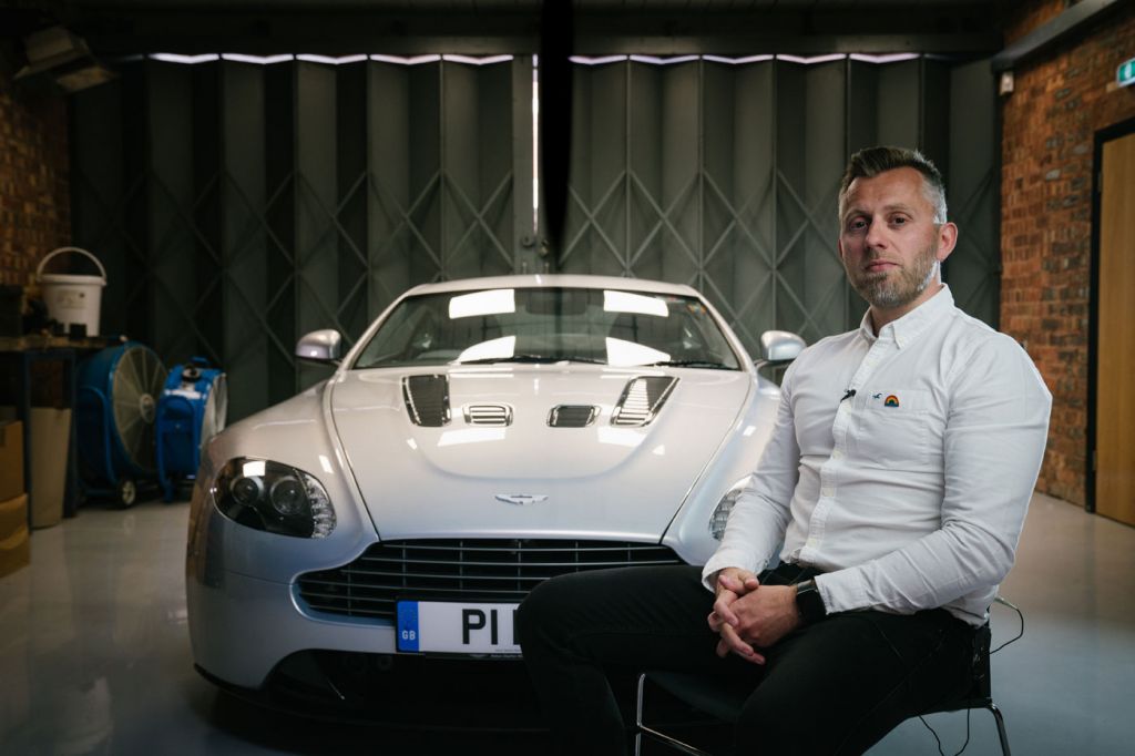 Nick Hobbis with a Vaughtons badge on an Aston Martin