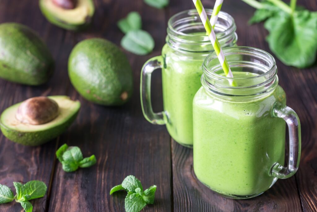Avocado smoothies in jars with straws
