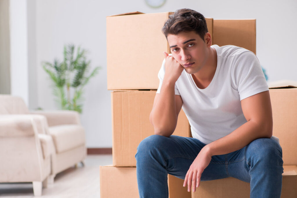 A young man sat on some boxes, unhappy his sale has fallen through