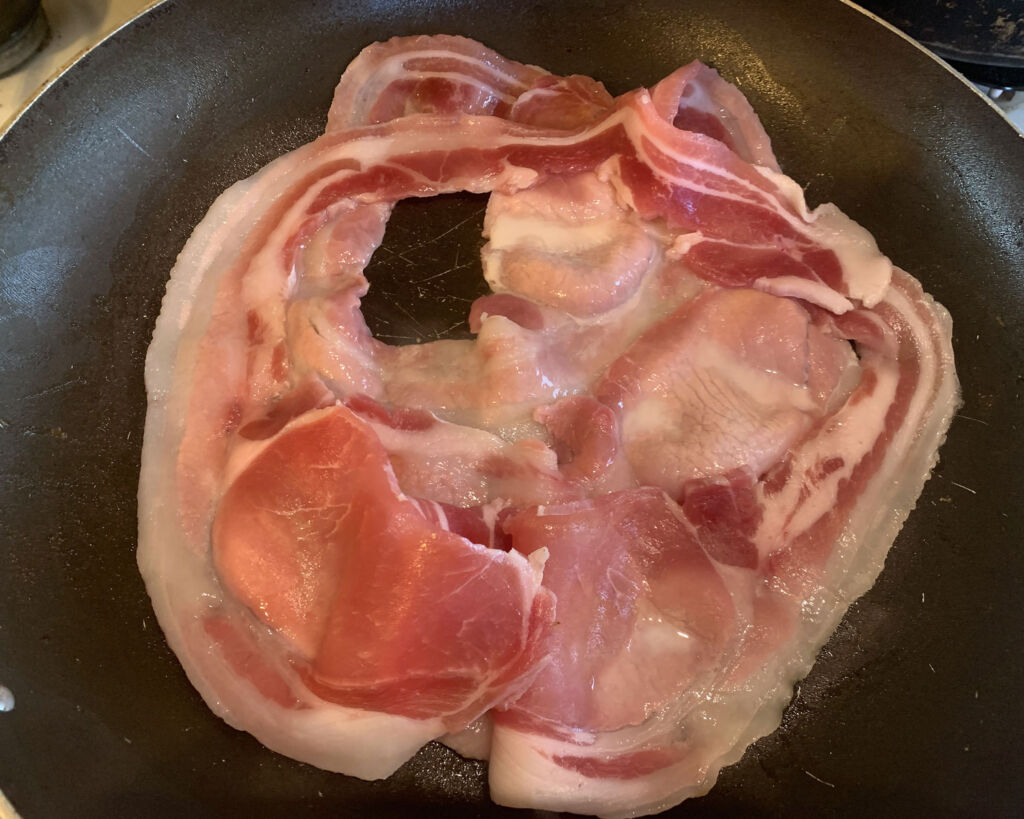 Rashers of bacon frying in a pan