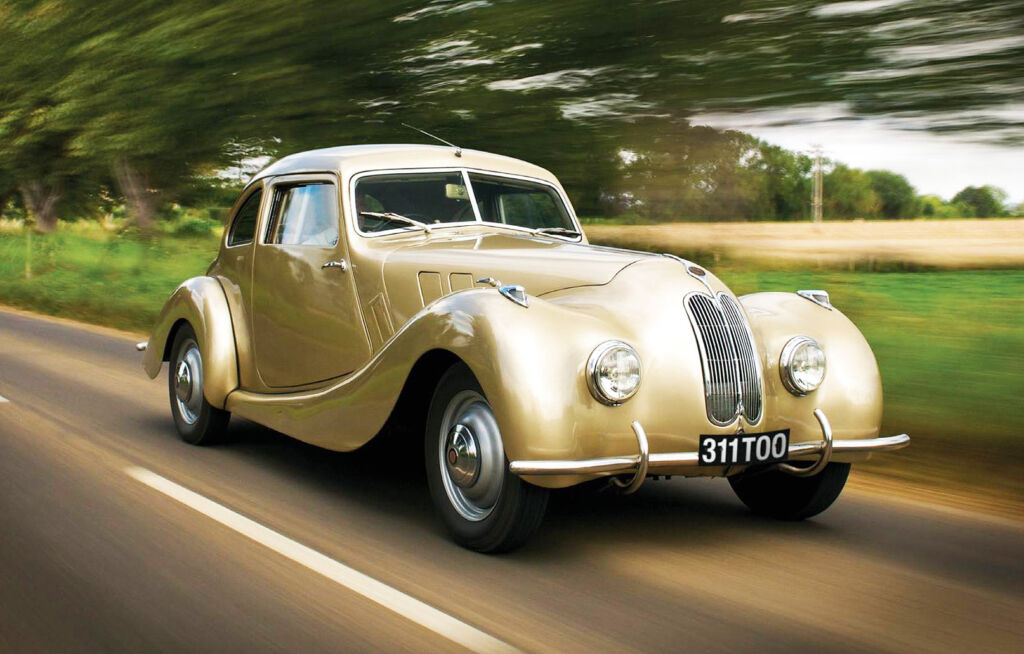 A classic Bristol Car in gold paint driving along country roads