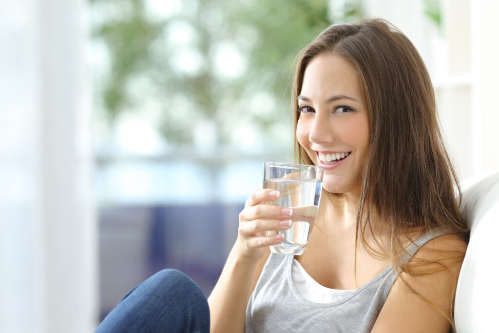 A young woman drinking a glass of water to stay hydrated