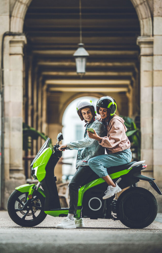 Young couple parked outside a historic building sat on the Silence S01 electric scooter