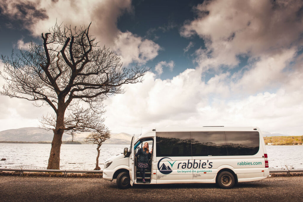 One of Rabbie's coaches parked by a lake with beautiful scenery all around