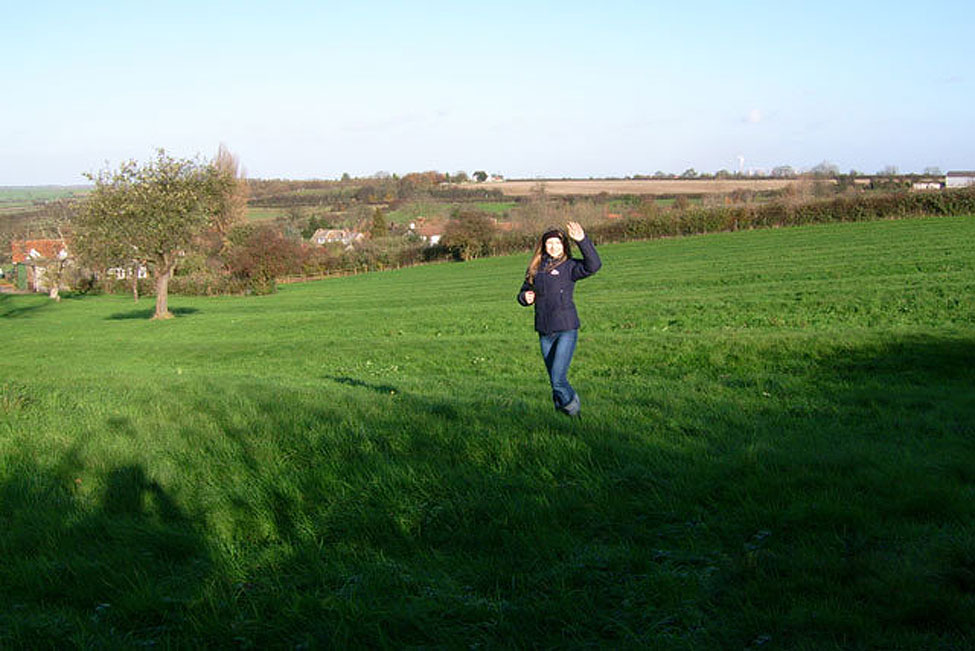 A woman standing in part of the extensve grounds at her property