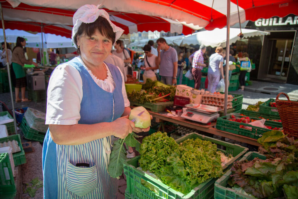 A woman selling local grown produce at a market stall