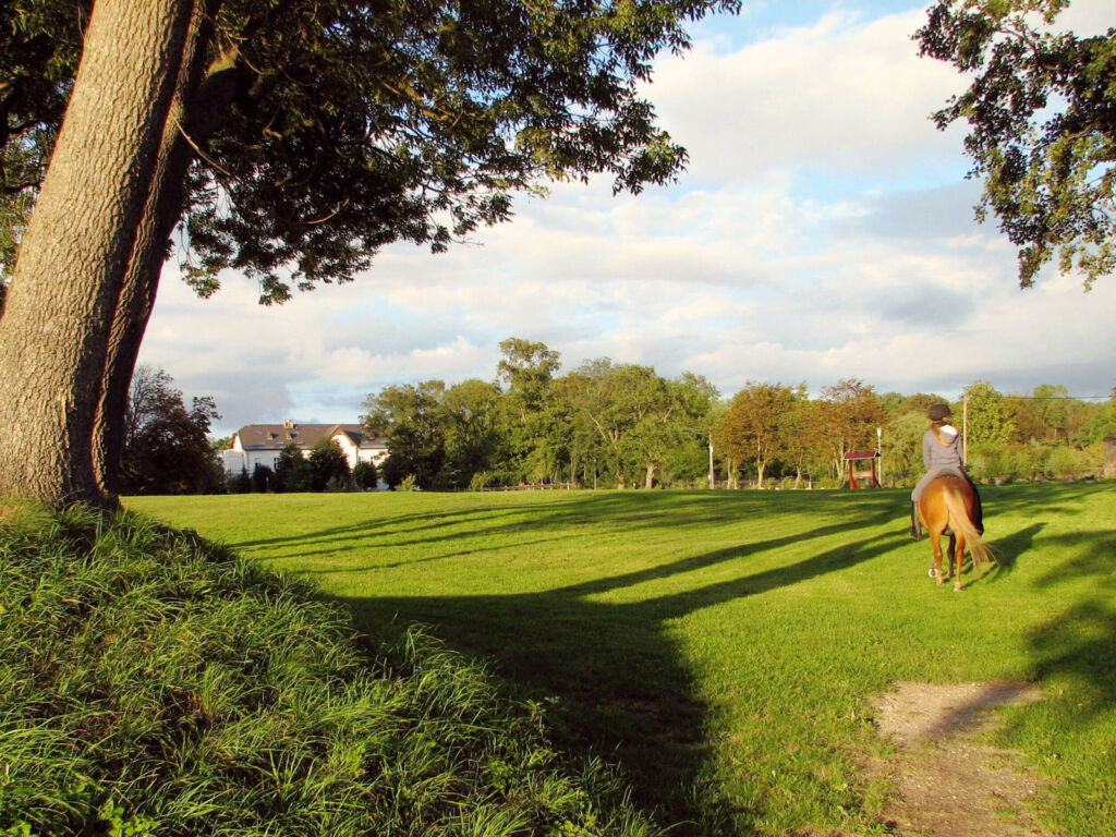 A guest riding a horse in the grounds of the manor house