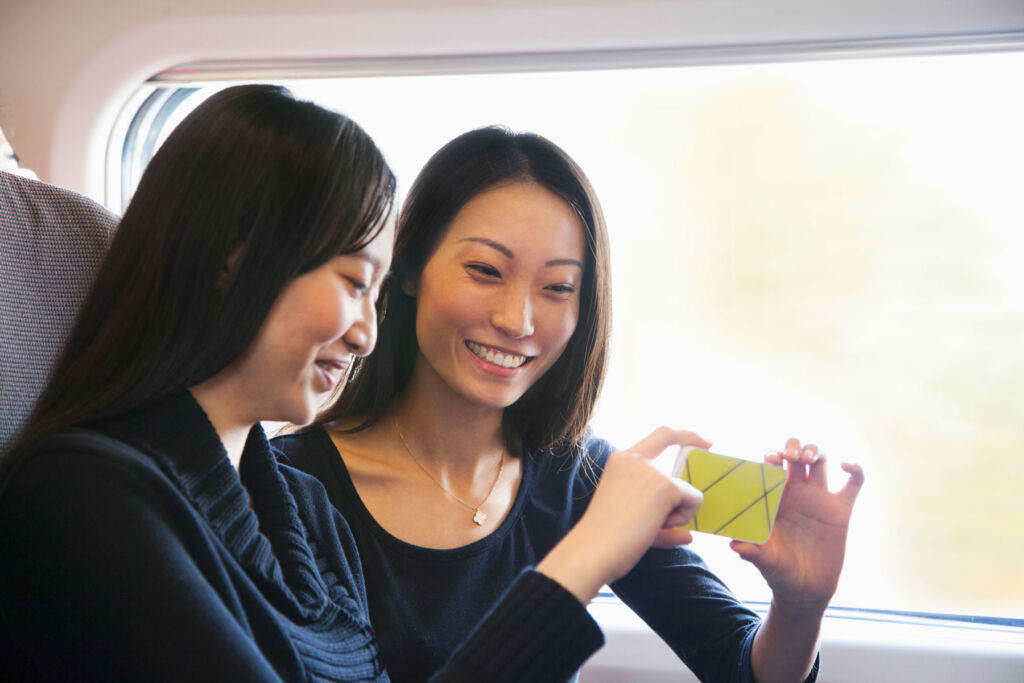 Two professional women on a train looking at a phone screen