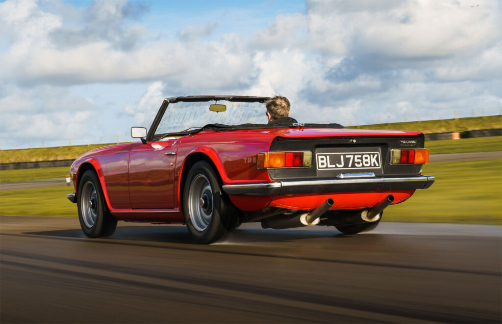 A Red triumph TR6 being driven at speed