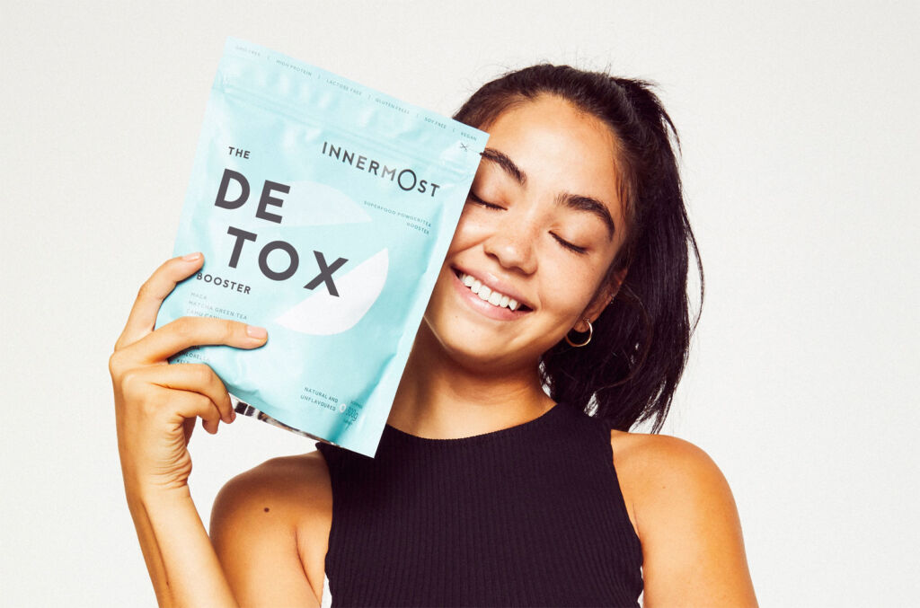 A woman holding the Innermost Detox product