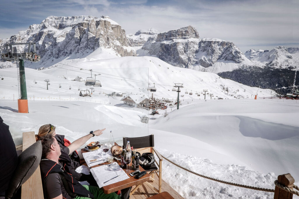 People enjoying a meal overlooking the snow at Val di Fassa