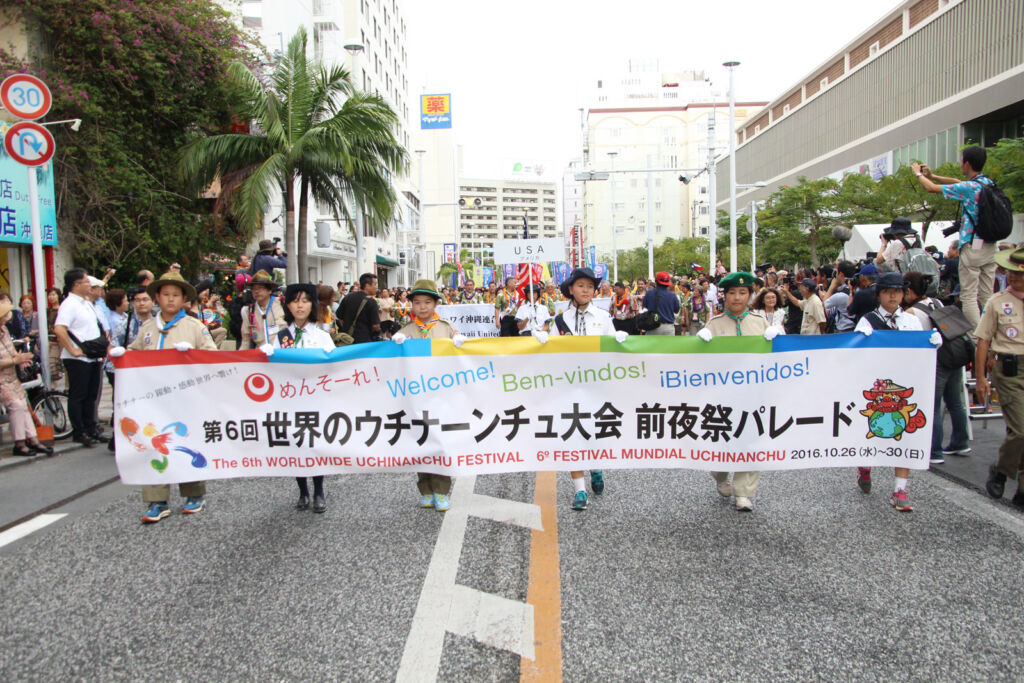 Young children marching with a banner at the Worldwide Uchinanchu Festival