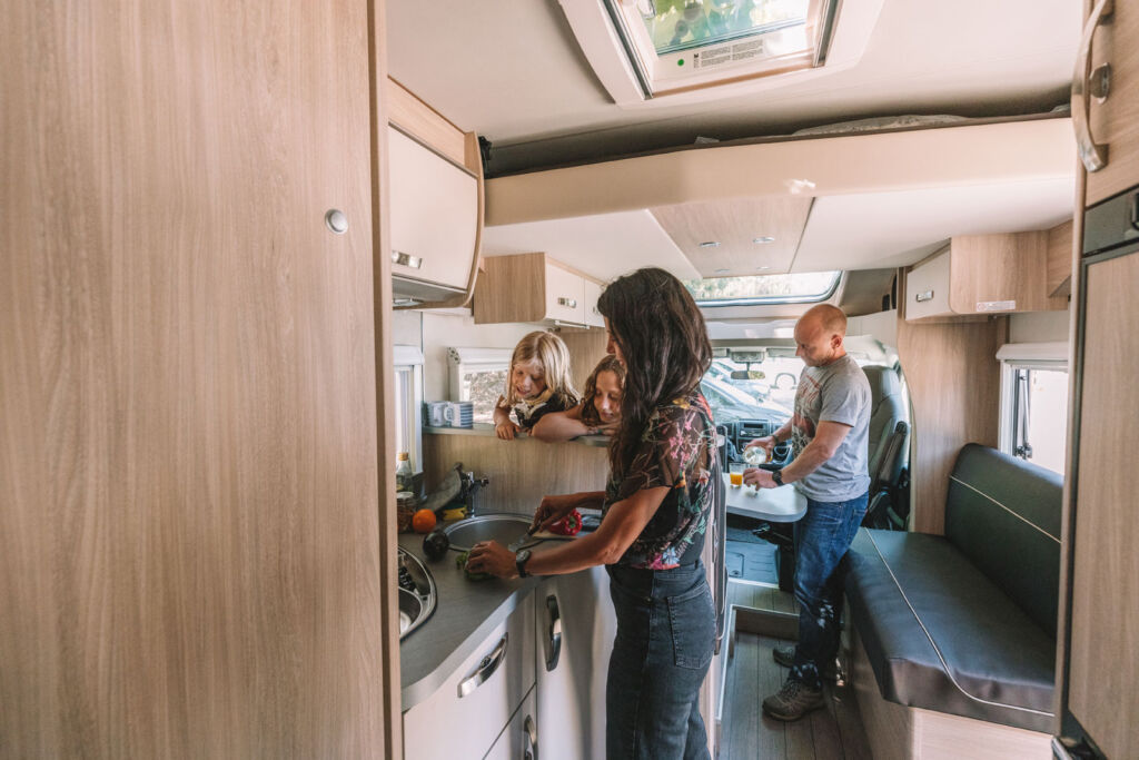 A mother teaching her children in a camper van kitchen