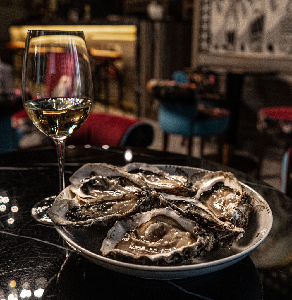 A plate of fresh oysters next to a glass of red wine