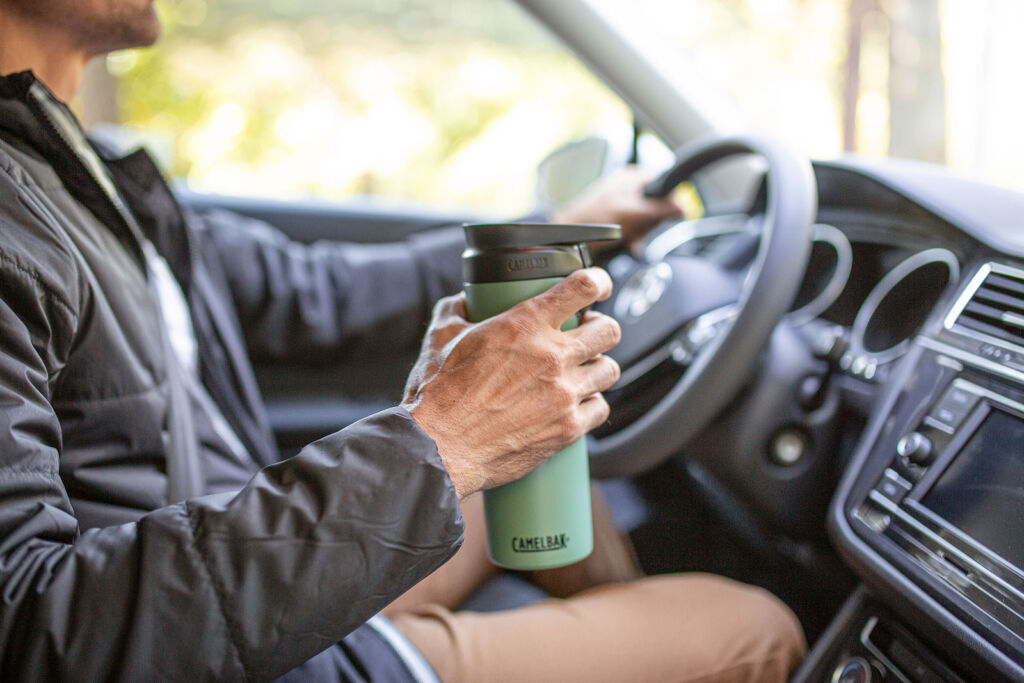 A man in his car showing how to operate the CamelBak Forge Flow Travel Mug