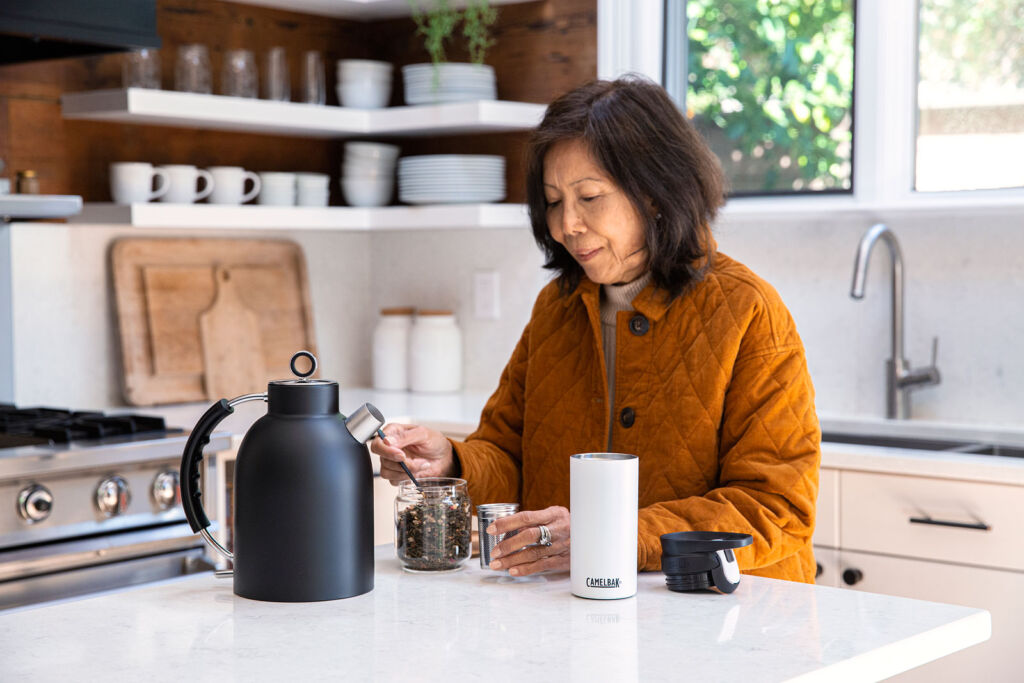 An older woman using the tea infuser in her kitchen