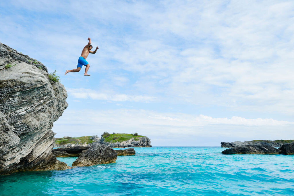 A man cliff jumping into the turquoise coloured sea
