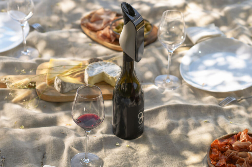 The Aerator fixed to the top of a bottle of wine in the sand at the beach