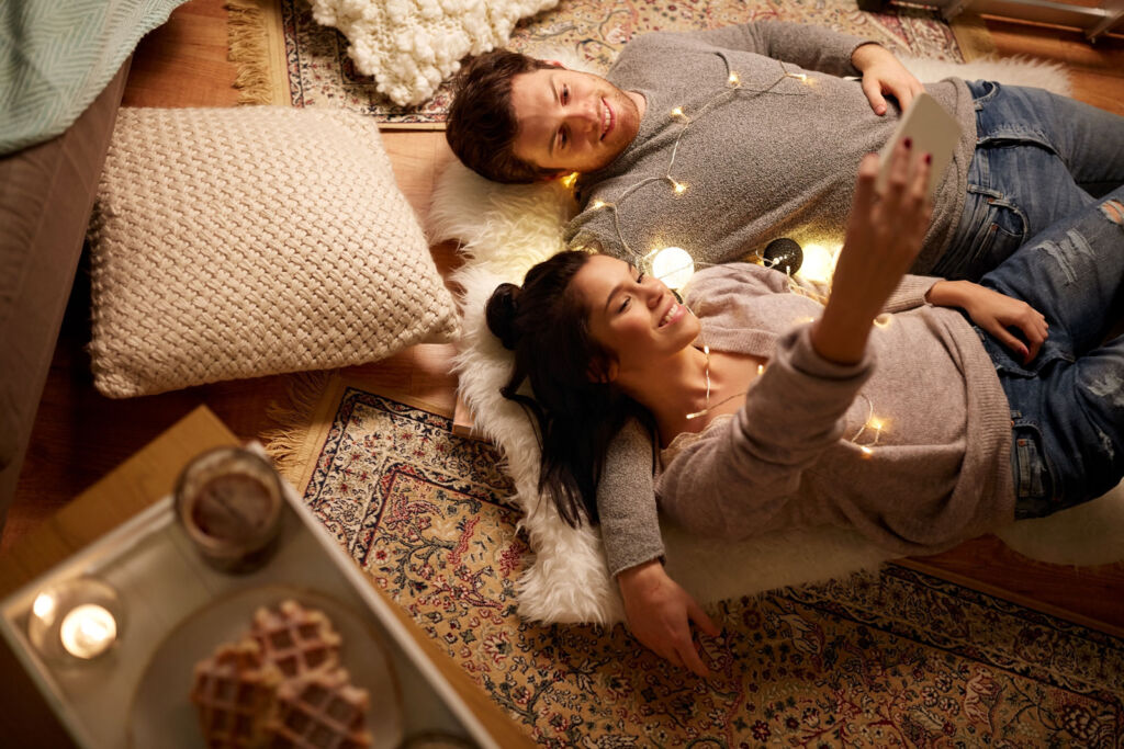A couple laying on the floor looking at a mobile phone screen before going to bed