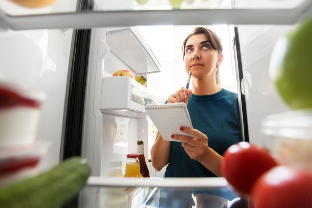 A woman working out what to do with the out of date food in her fridge