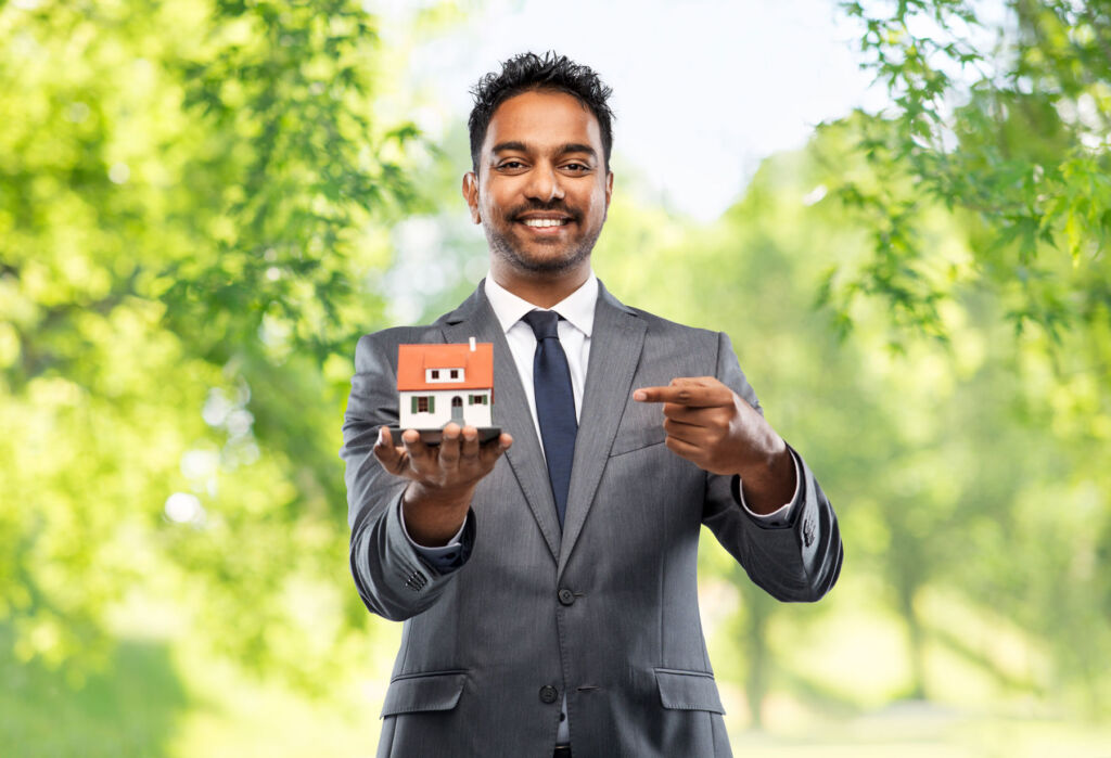 An estate agent holding a small property model in his hand