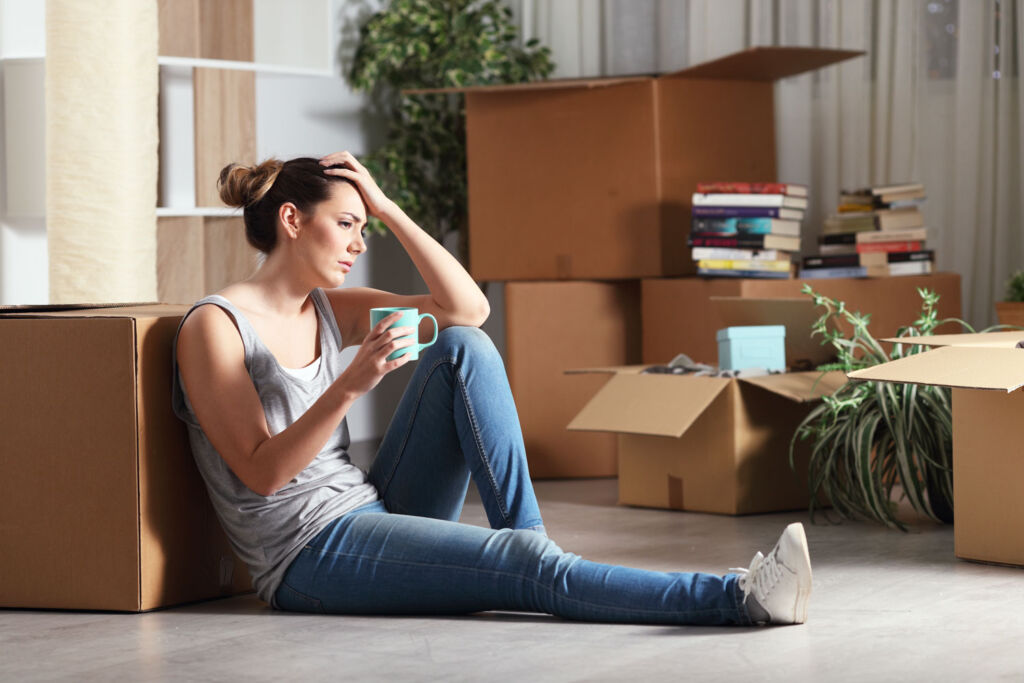 A stressed woman sat on the floor in her new home surrounded by boxes