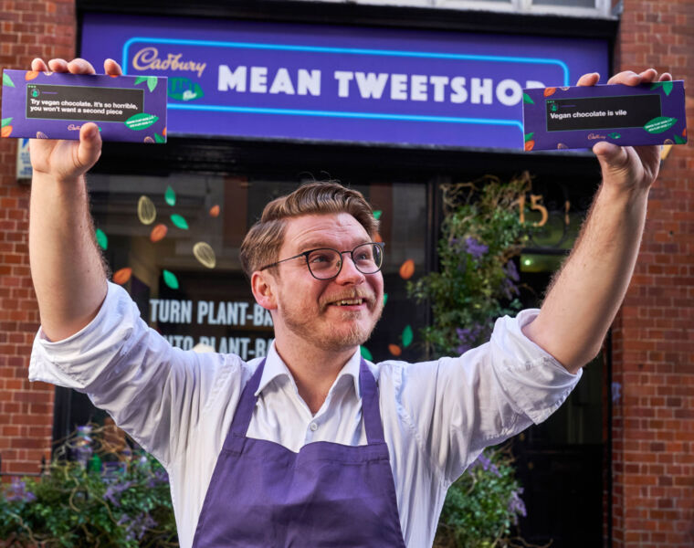 A man holding bars above his head at the Mean Tweetshop