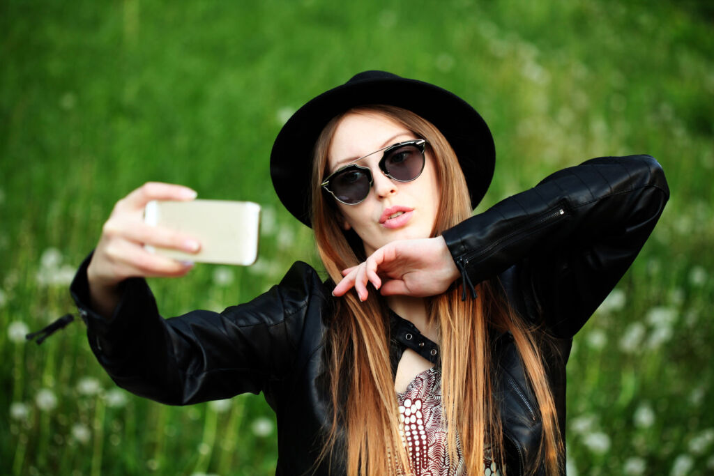 A young woman taking a photograph of herself outdoors for social media