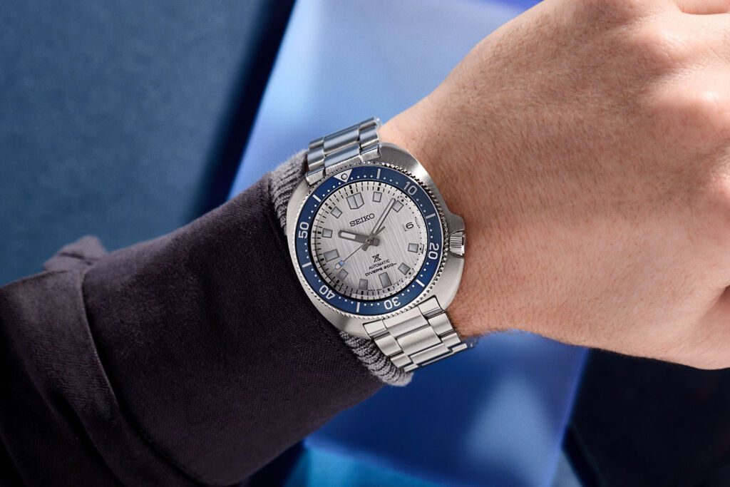 The Seiko Save the Ocean watch in steel with a white dial and blue bezel