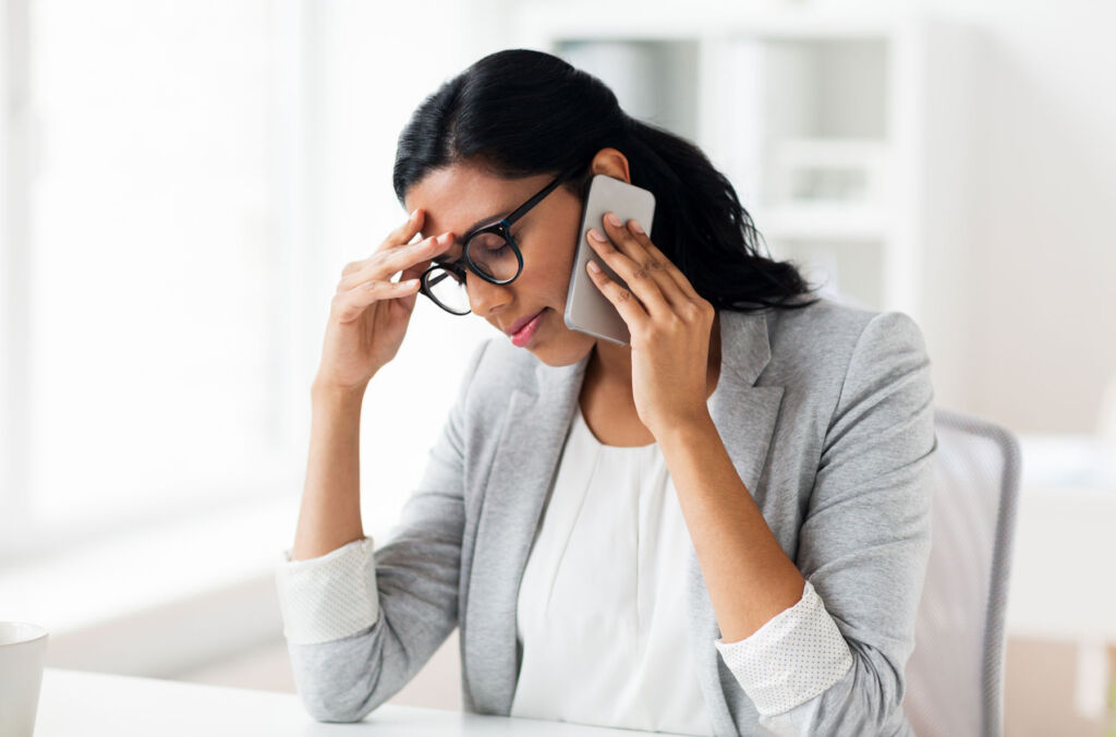 A woman in her office suffering from brain fog on the phone