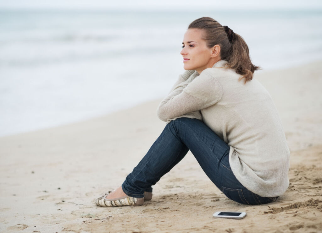A woman sat on a beach, deep in thought