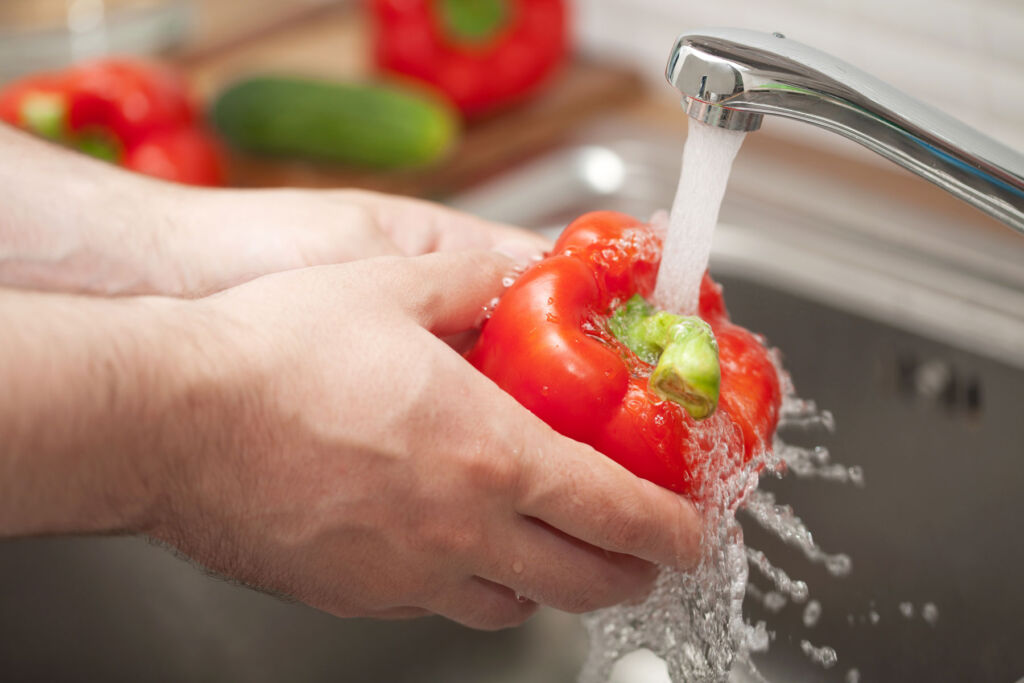 Running water from a tap on a red pepper