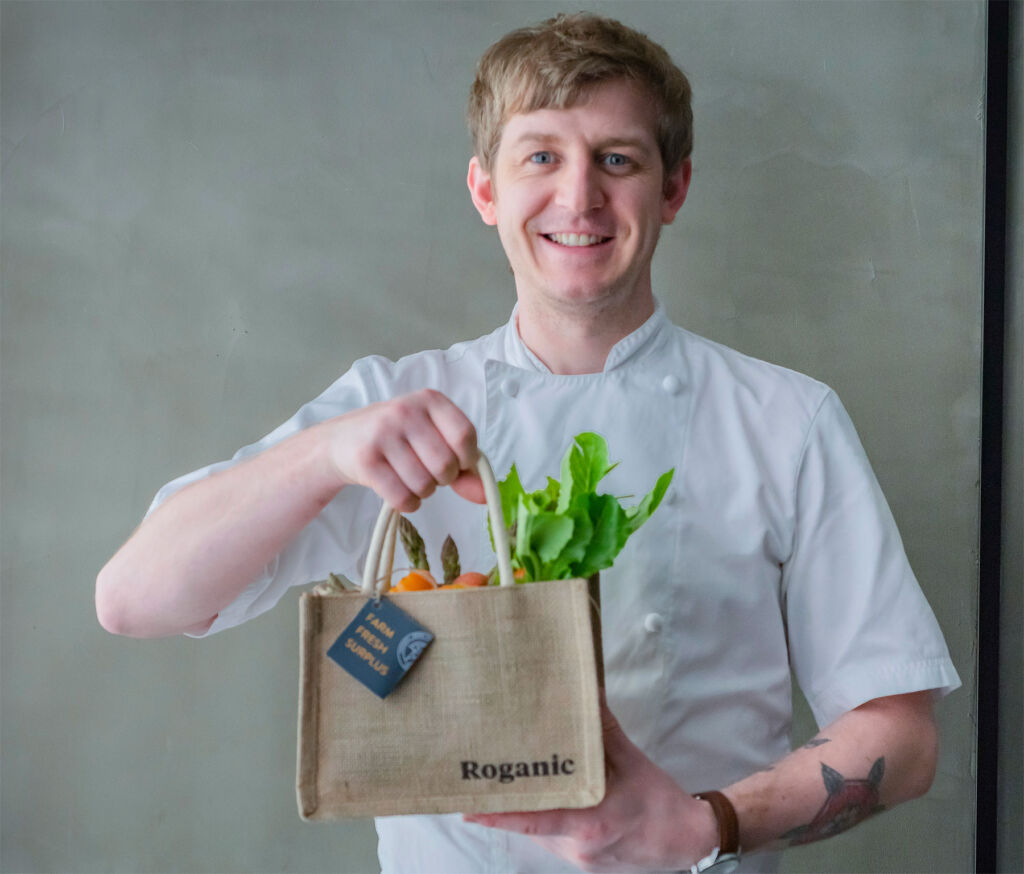 One of the chefs holding a bag filled with vegetables