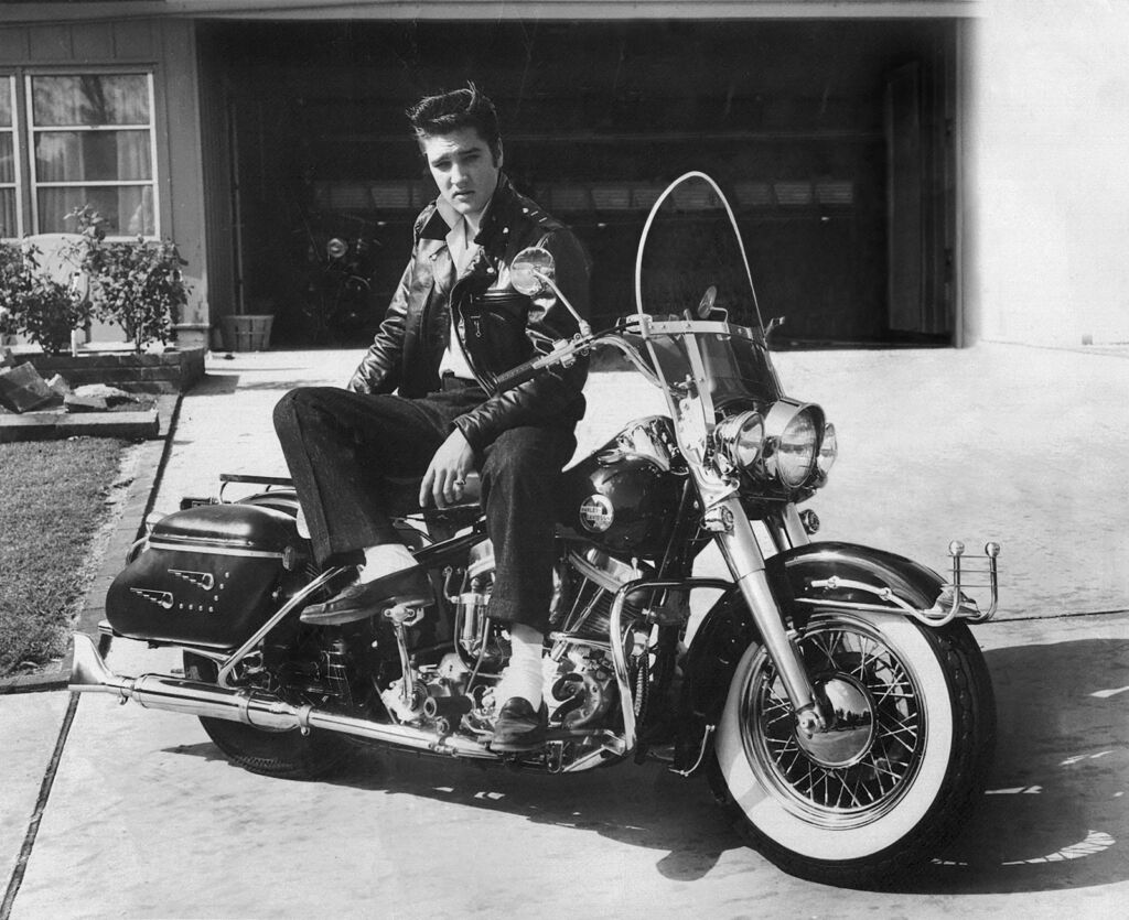 A black and white photo showing young Presley sat on a Harley Davidson motorcycle