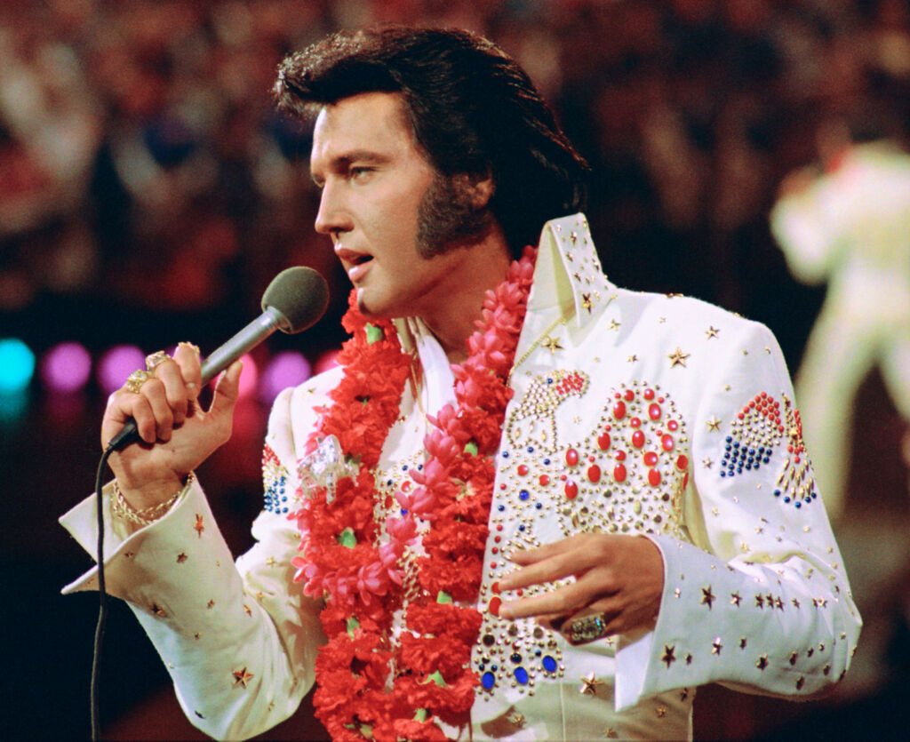 Presley performing in his iconic white rhinestone encrusted jumpsuit