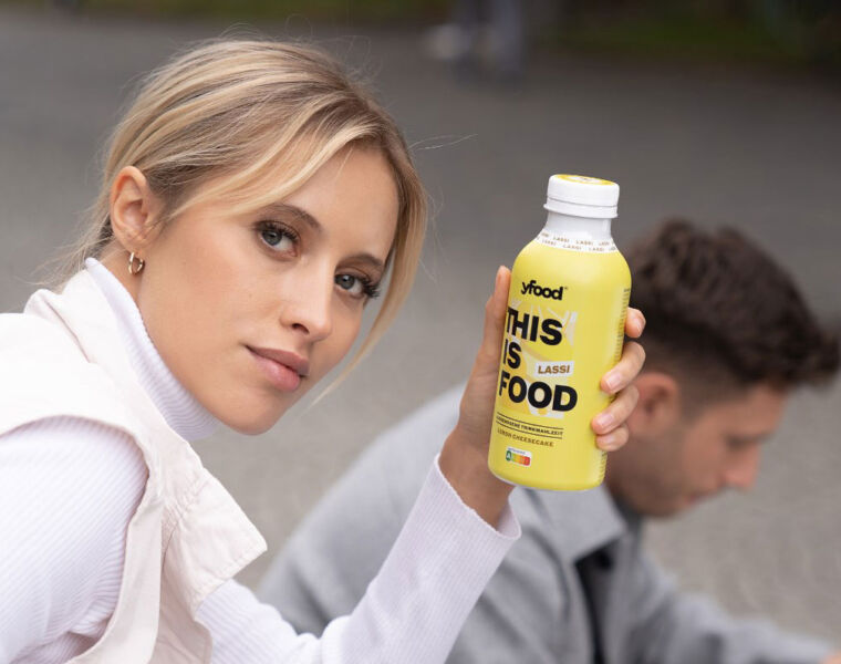 A woman holding a bottle of yfood Lemon cheesecake drink
