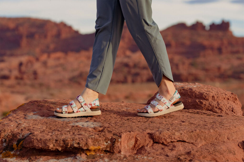 The footwear brand has focused on all-around accessibility with its new sandals, in this image, a woman is walking along rocky cliff tops