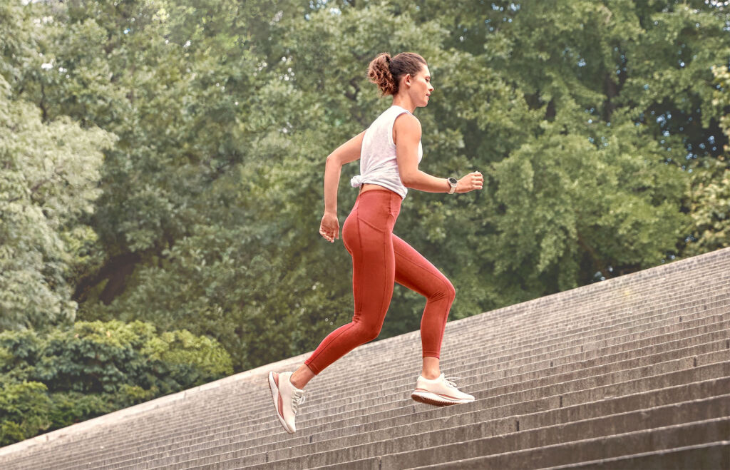 A woman exercising up an down steps wearing a Garmin watch
