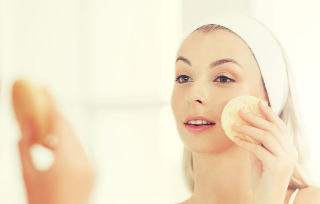 A woman exfoliating her skin in the mirror