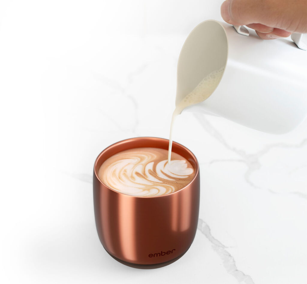Someone pouring milk into an ornate pattern into the smart mug