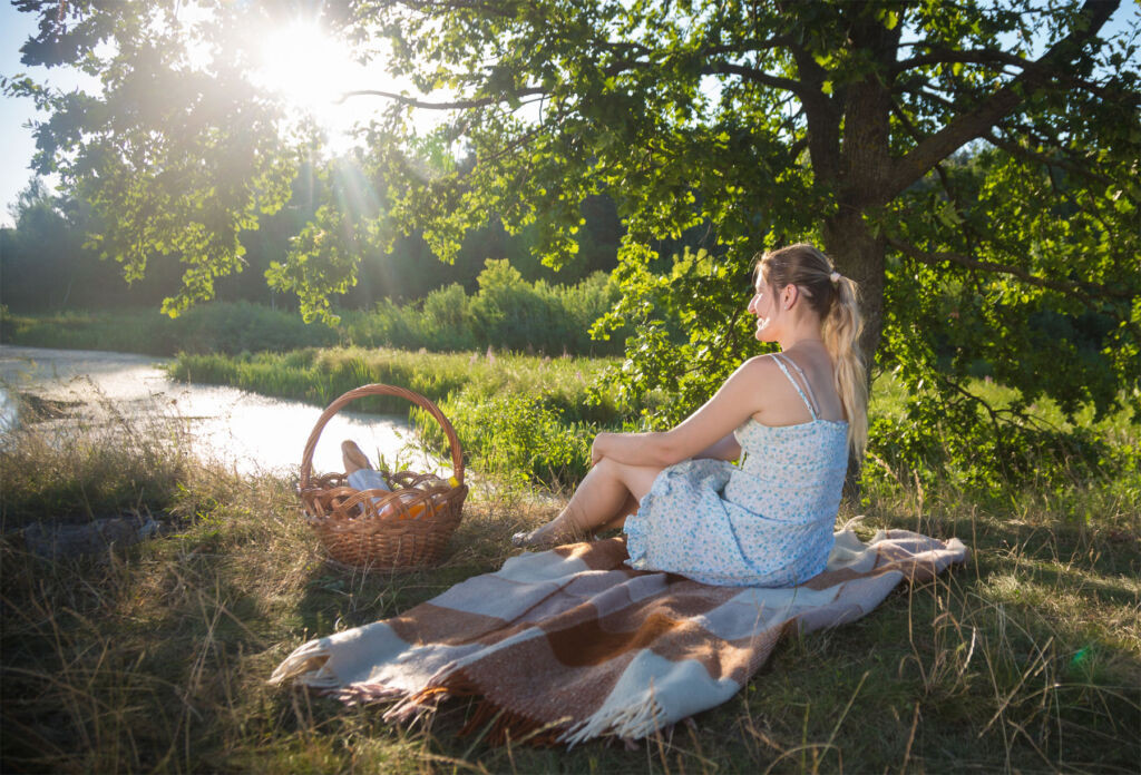 A woman enjoying a picnic in the countryside by a river