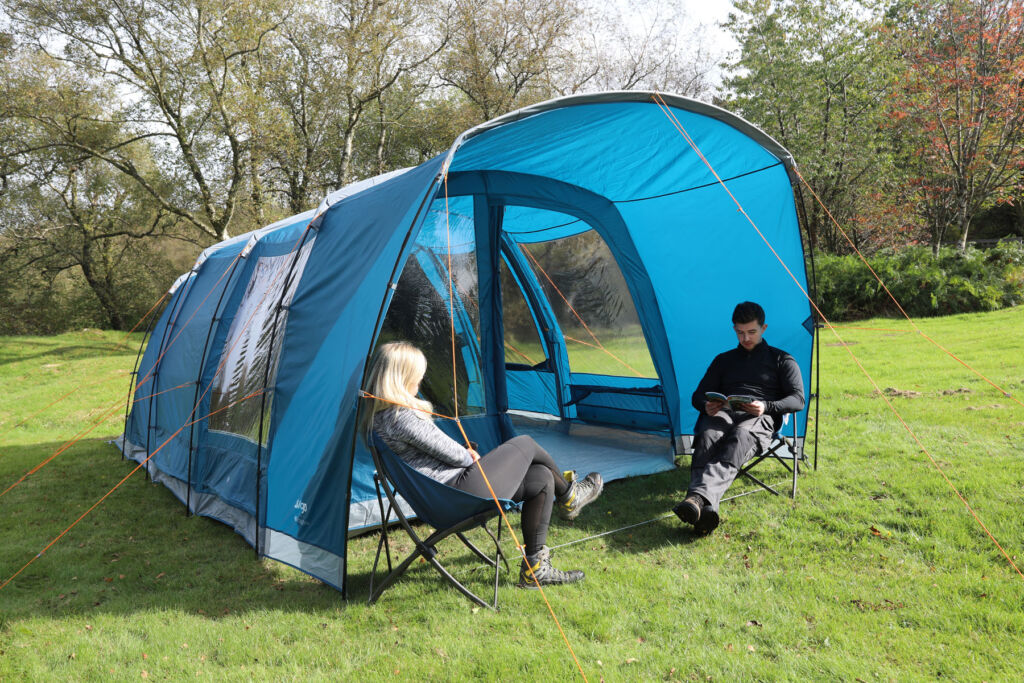 A couple sat outside a large blue poled tent