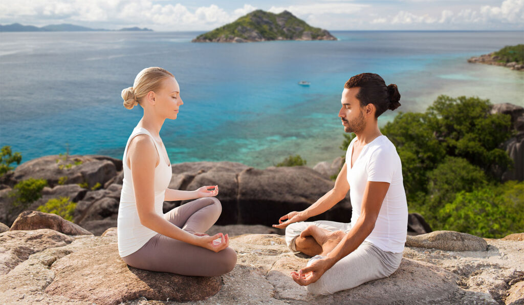 A man and a woman meditating on a clifftop