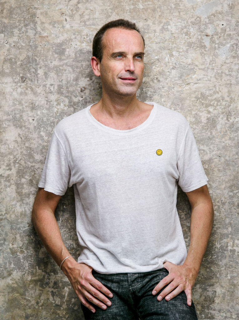 Nicolas wearing a white t-shirt with his world famous logo and jeans