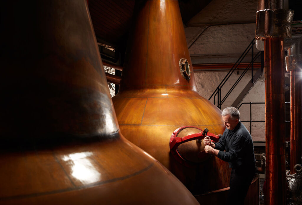 A man examining the copper stills at the distillery
