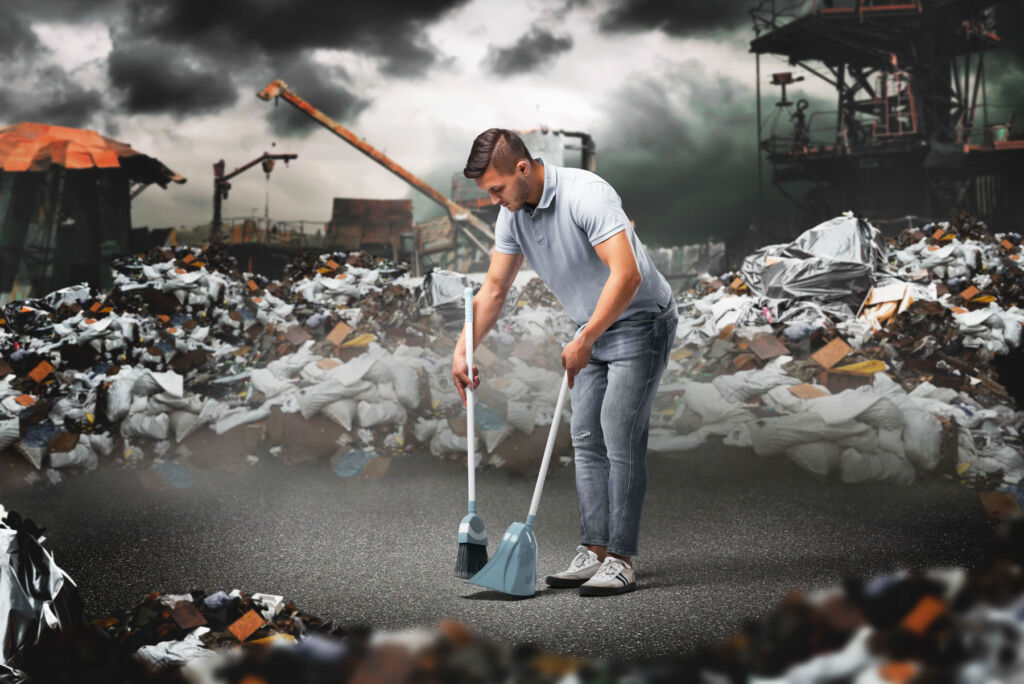 A man sweeping up discarded electric parts at a recycling centre