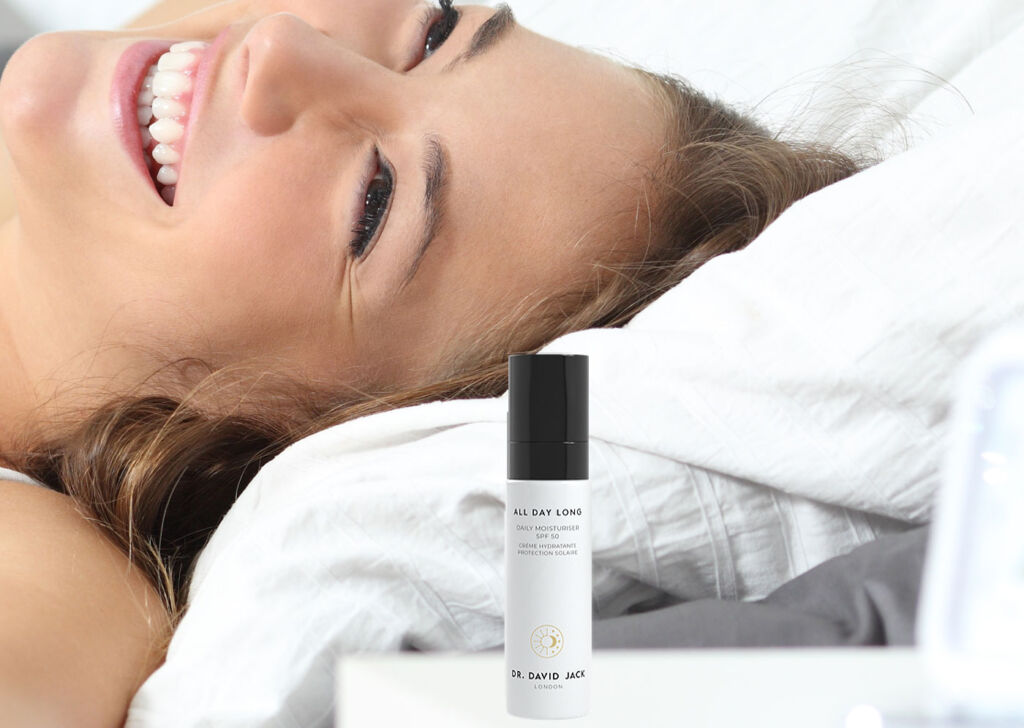 A young woman waking up in bed with Dr. David Jack's All Day Long formula on her bedside table