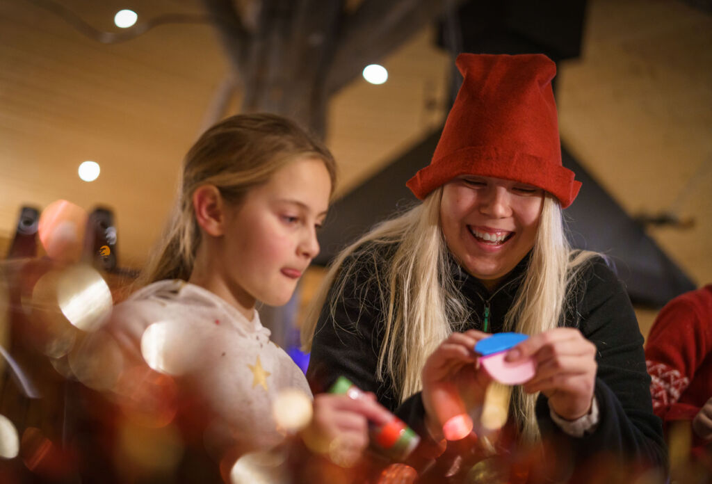 A young girl making toys with one of the elves